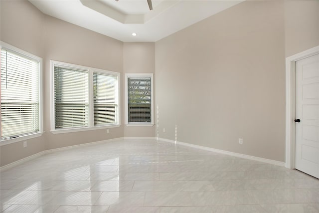 spare room featuring ceiling fan, a healthy amount of sunlight, and a tray ceiling