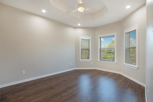 spare room featuring a raised ceiling, dark hardwood / wood-style floors, and ceiling fan