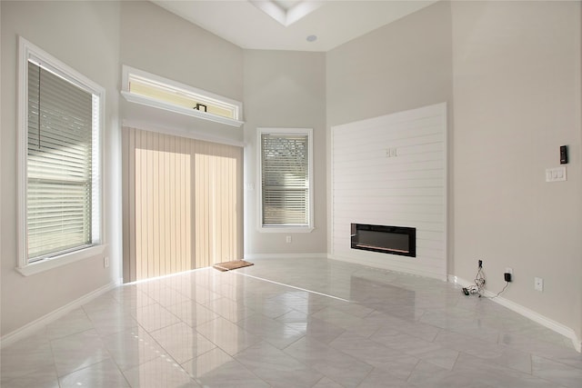 unfurnished living room with a large fireplace, light tile patterned floors, and a wealth of natural light