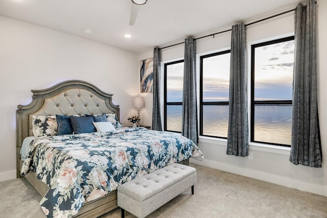 bedroom featuring a water view, ceiling fan, and light carpet