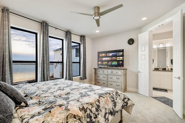 bedroom featuring light carpet, connected bathroom, and ceiling fan