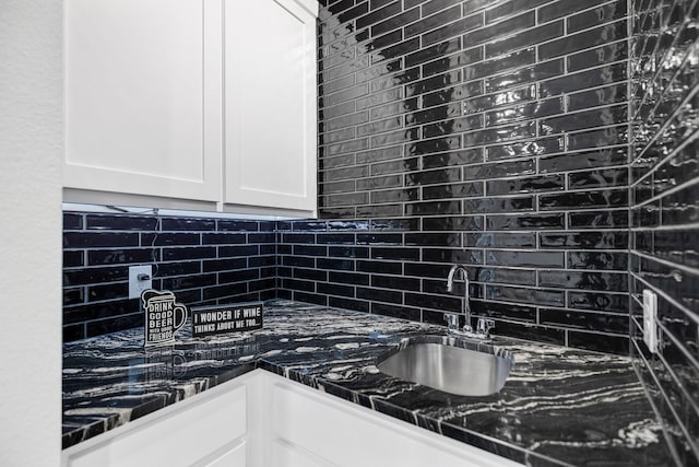 kitchen featuring dark stone counters, sink, decorative backsplash, and white cabinets