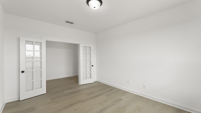 unfurnished bedroom with light wood finished floors, baseboards, visible vents, and french doors