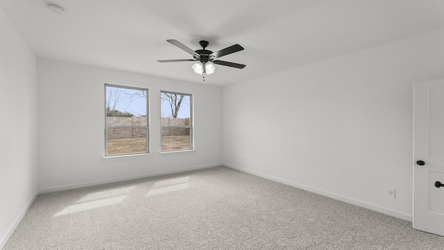 spare room with a ceiling fan, light colored carpet, and baseboards