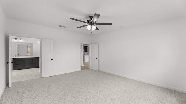 unfurnished bedroom featuring baseboards, ensuite bathroom, visible vents, and light colored carpet