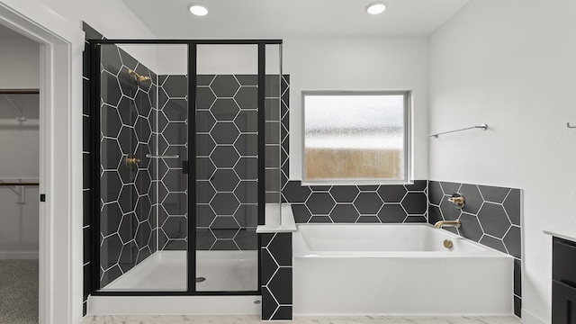 bathroom with recessed lighting, a garden tub, a shower stall, and a spacious closet