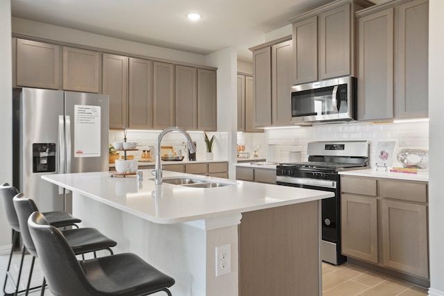 kitchen with an island with sink, appliances with stainless steel finishes, a breakfast bar, and sink