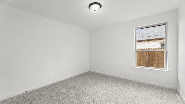 unfurnished room featuring carpet and baseboards