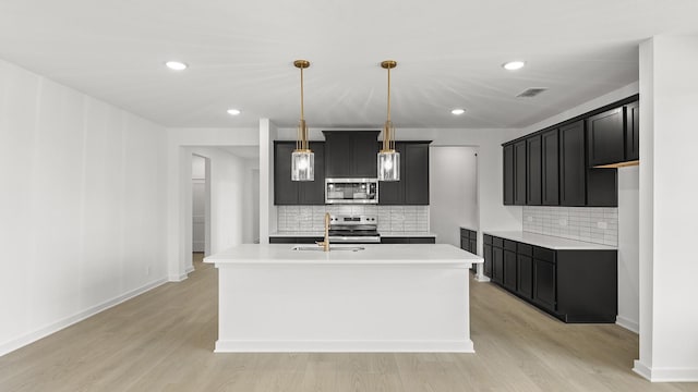 kitchen featuring light wood-style flooring, stainless steel appliances, a sink, and light countertops