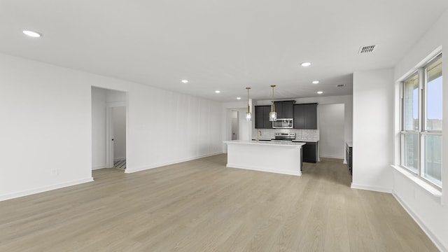 kitchen with visible vents, open floor plan, light countertops, light wood-type flooring, and stainless steel microwave