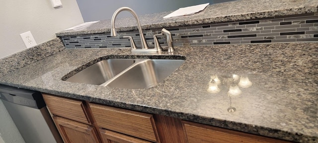 kitchen featuring stainless steel dishwasher, sink, and dark stone countertops