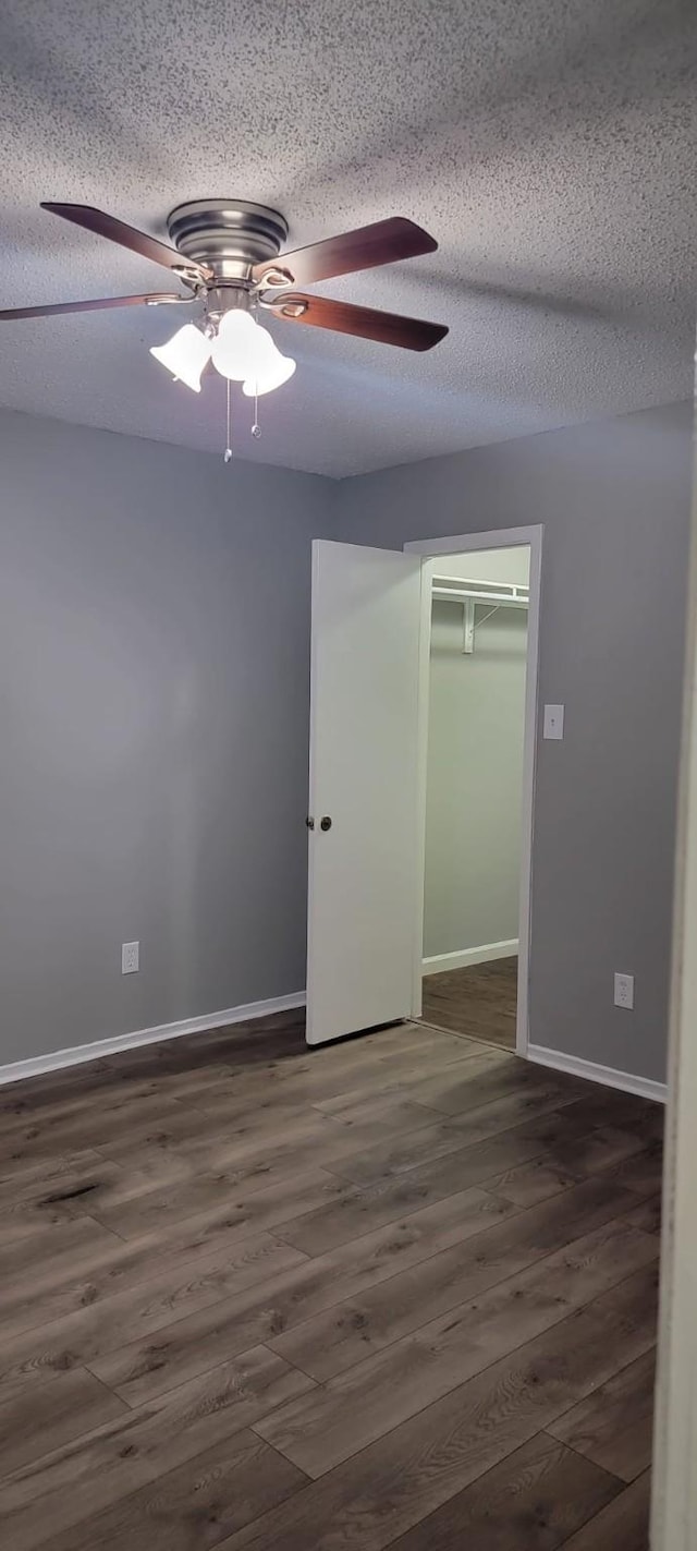 unfurnished bedroom featuring ceiling fan, a textured ceiling, dark hardwood / wood-style flooring, and a closet