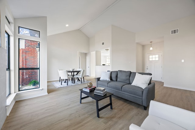 living room with high vaulted ceiling and light hardwood / wood-style flooring