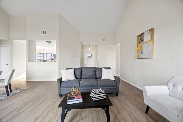 living room with hardwood / wood-style floors, a notable chandelier, and high vaulted ceiling