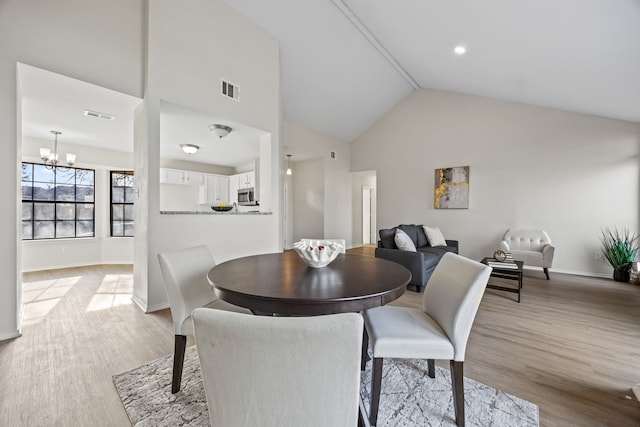 dining space with high vaulted ceiling, a chandelier, and light wood-type flooring