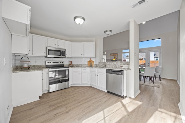 kitchen featuring sink, white cabinetry, stainless steel appliances, light hardwood / wood-style floors, and light stone countertops