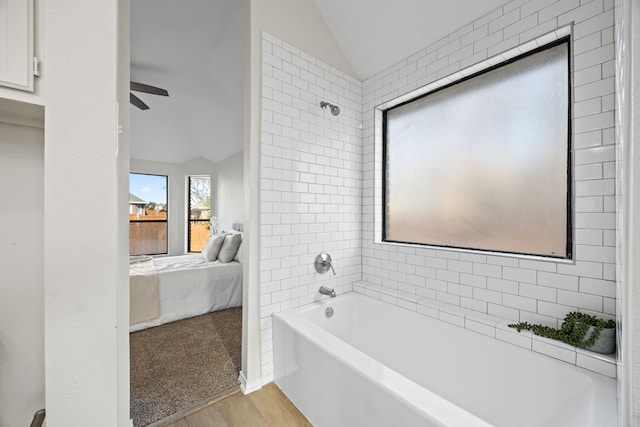 bathroom with ceiling fan, lofted ceiling, tiled shower / bath combo, and wood-type flooring