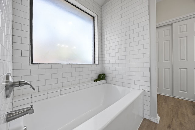 bathroom with hardwood / wood-style flooring and a tub