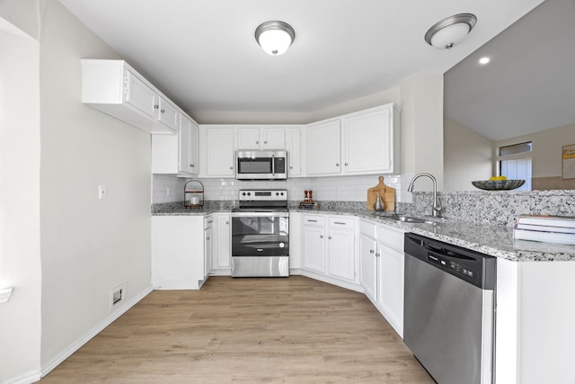 kitchen featuring appliances with stainless steel finishes, light stone countertops, sink, and white cabinets