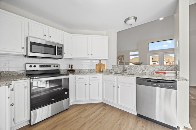 kitchen featuring appliances with stainless steel finishes, sink, light hardwood / wood-style flooring, and white cabinets