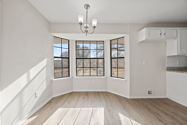 unfurnished dining area featuring a chandelier and light wood-type flooring