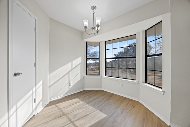 unfurnished dining area with a healthy amount of sunlight, a chandelier, and light wood-type flooring