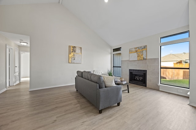 living room with high vaulted ceiling, hardwood / wood-style flooring, and a tile fireplace