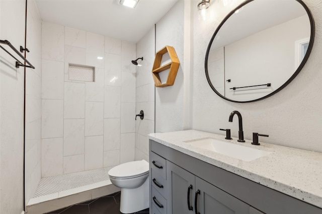 bathroom with tile patterned floors, vanity, toilet, and a tile shower