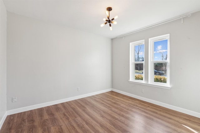 spare room with an inviting chandelier and hardwood / wood-style flooring