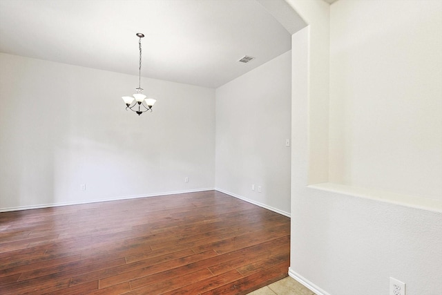 spare room with hardwood / wood-style flooring and a notable chandelier