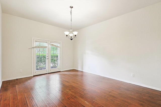 empty room featuring wood-type flooring and a chandelier