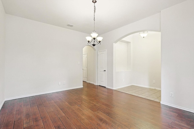 empty room featuring hardwood / wood-style flooring and a notable chandelier