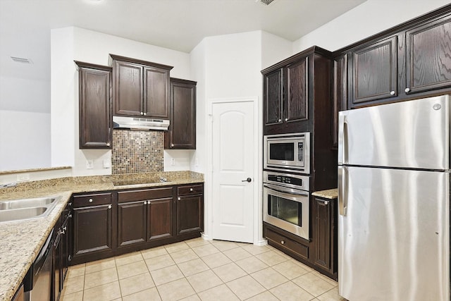 kitchen with appliances with stainless steel finishes, tasteful backsplash, sink, light tile patterned floors, and light stone counters