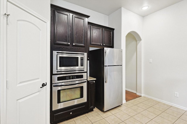 kitchen with appliances with stainless steel finishes, dark brown cabinets, and light tile patterned floors