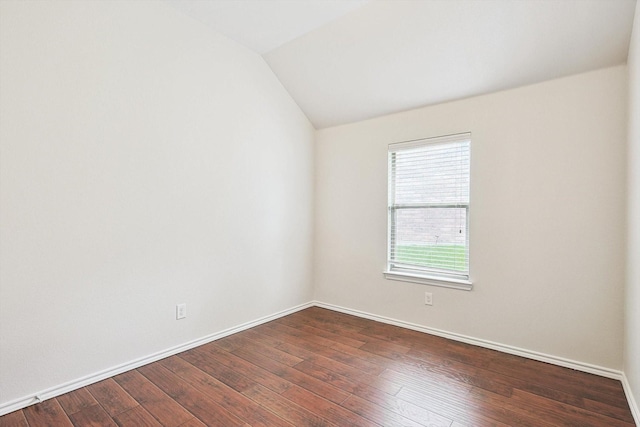 spare room featuring vaulted ceiling and dark hardwood / wood-style flooring