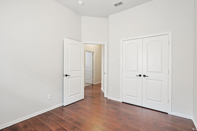 unfurnished bedroom with dark hardwood / wood-style floors and a closet