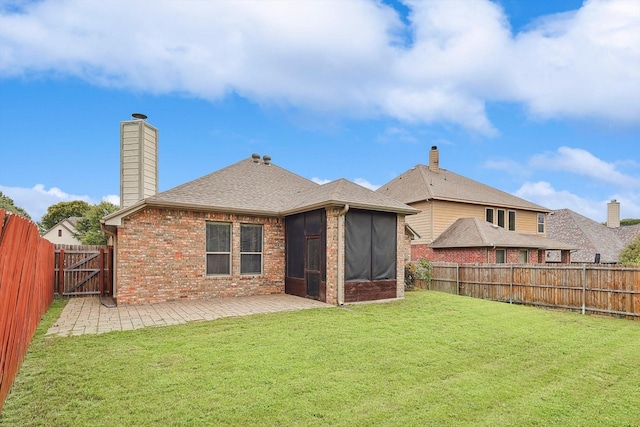 rear view of house with a sunroom, a yard, and a patio area