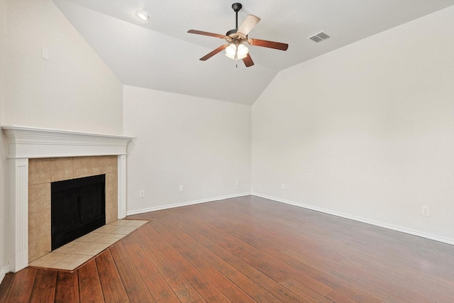 unfurnished living room featuring a tiled fireplace, lofted ceiling, ceiling fan, and light hardwood / wood-style flooring