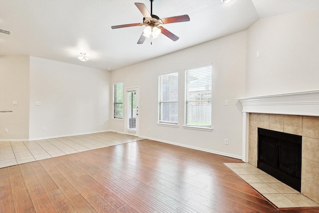 unfurnished living room with ceiling fan, lofted ceiling, a fireplace, and light hardwood / wood-style floors