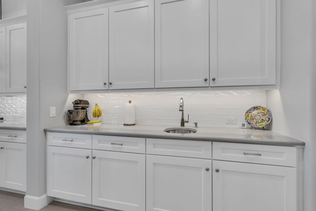 bar featuring white cabinetry, sink, and tasteful backsplash