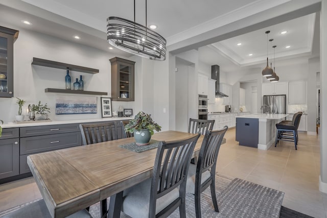 tiled dining space with crown molding, a raised ceiling, and sink