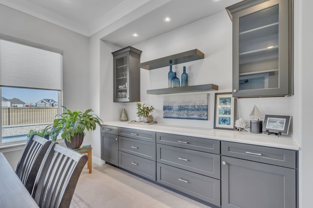 bar with gray cabinetry and ornamental molding