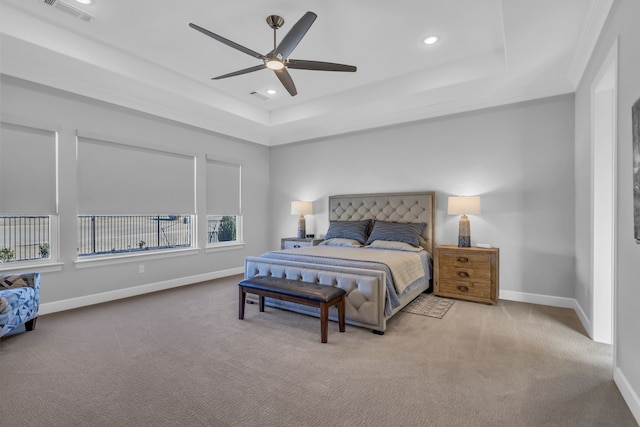 bedroom with a tray ceiling, light colored carpet, and ceiling fan