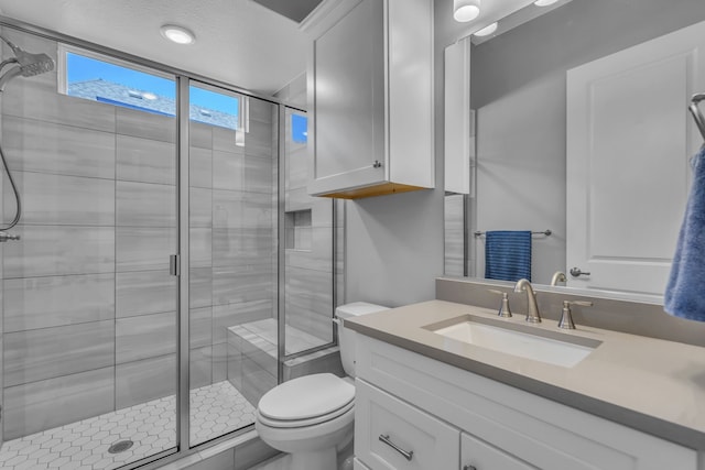 bathroom with a shower with door, vanity, and toilet