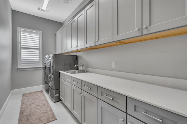 clothes washing area featuring sink, cabinets, washing machine and clothes dryer, and light tile patterned flooring