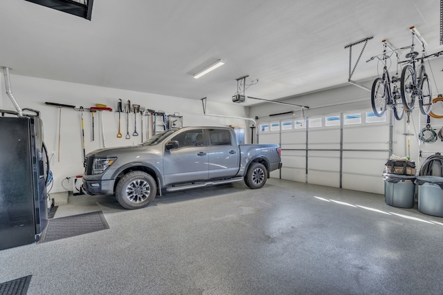 garage with a garage door opener and black refrigerator with ice dispenser