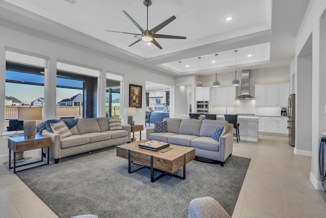 tiled living room featuring a raised ceiling and ceiling fan