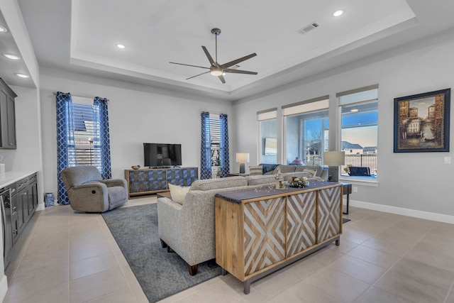 living room featuring light tile patterned flooring, ceiling fan, and a tray ceiling