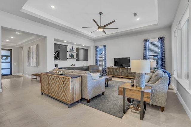 living room featuring a tray ceiling, tile patterned floors, and ceiling fan