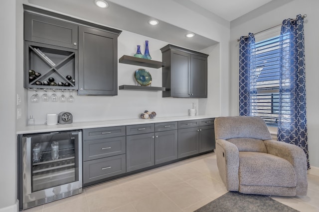 bar featuring beverage cooler, light tile patterned floors, and gray cabinetry